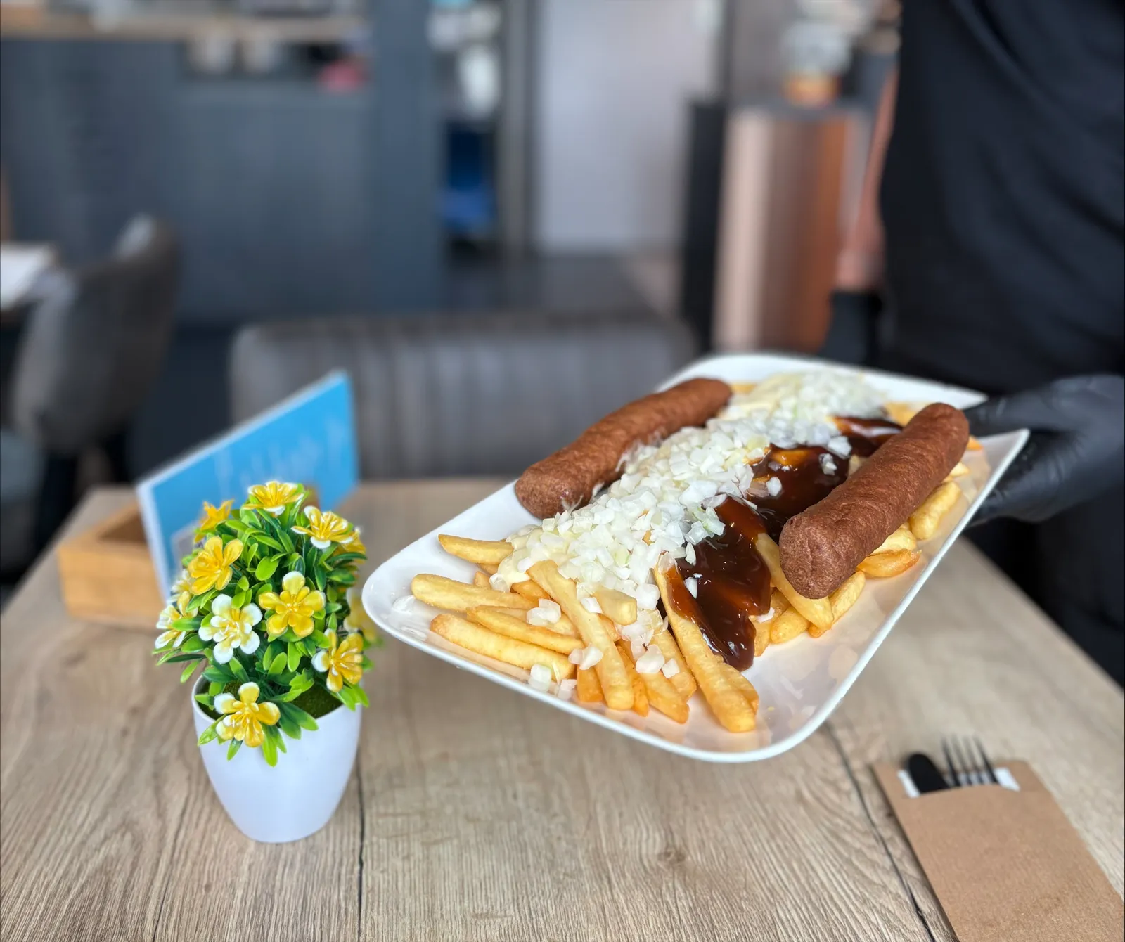 Schaal met frikandellen, frites, ui en saus op tafel in de cafetaria