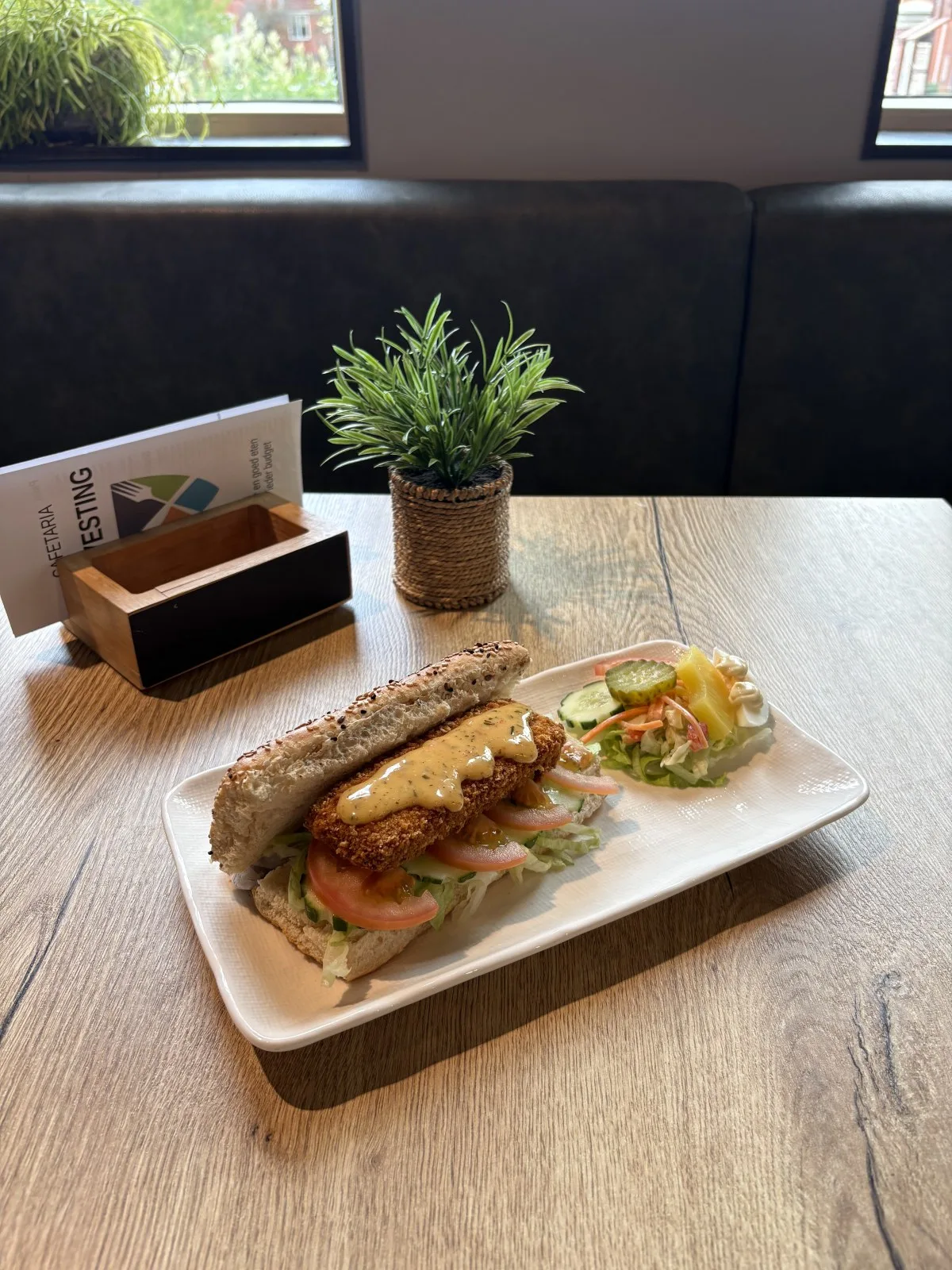 Broodje Kipcrush met sla, tomaat, komkommer en jamballasaus op een sesambroodje