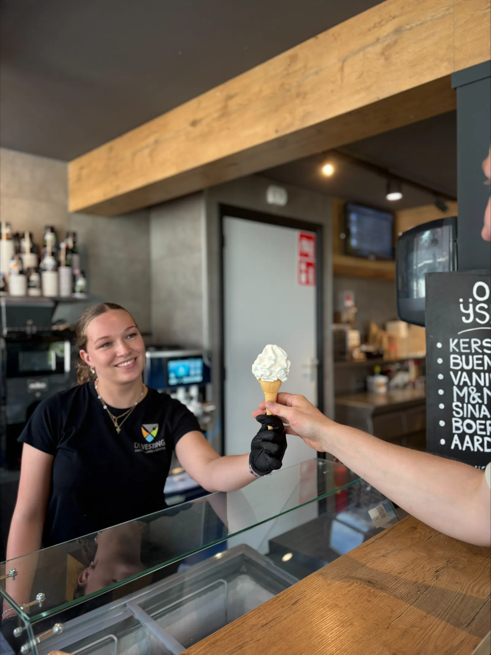 Medewerker van De Vesting geeft een softijsje aan over de balie